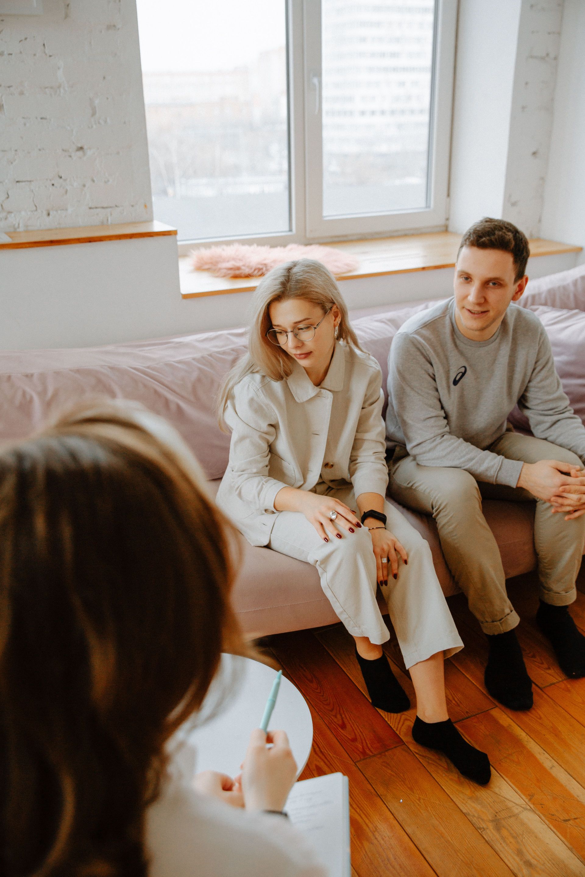 A couple in a counseling session with a therapist in a cozy, modern room.